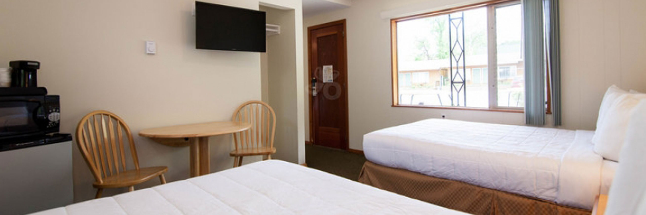 A hotel room with two beds, a table, and a TV.