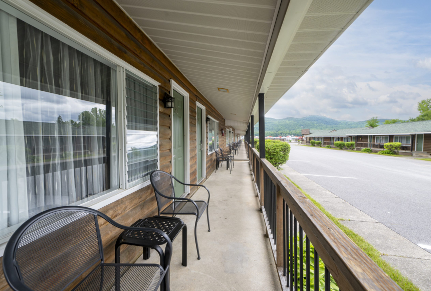 A balcony with black chairs and a view of mountains and a road.