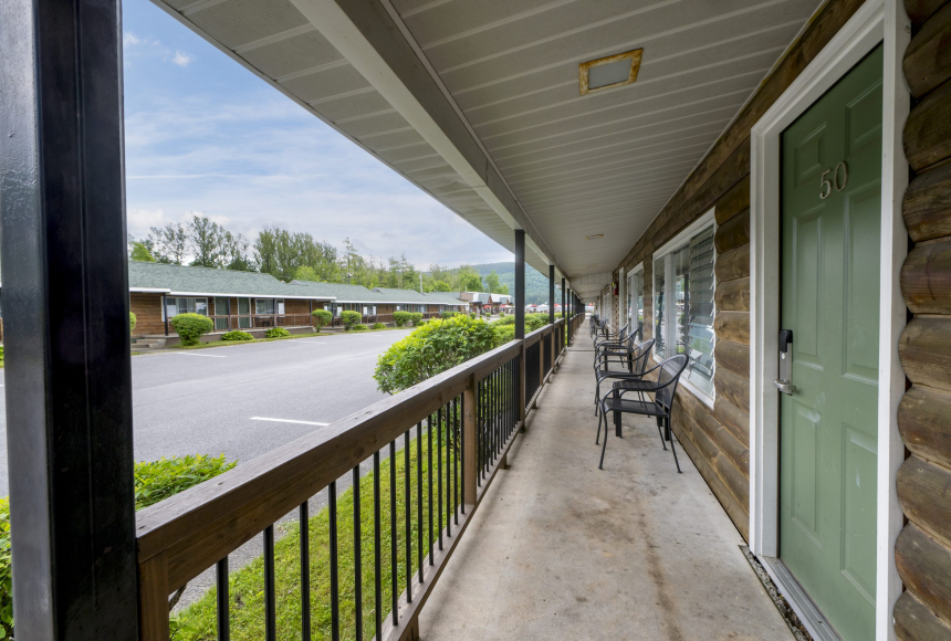A covered balcony with a green door and a view of the parking lot.