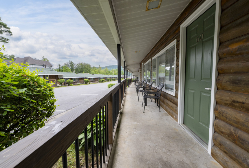 A log cabin balcony with outdoor seating and a view of the surrounding mountains.