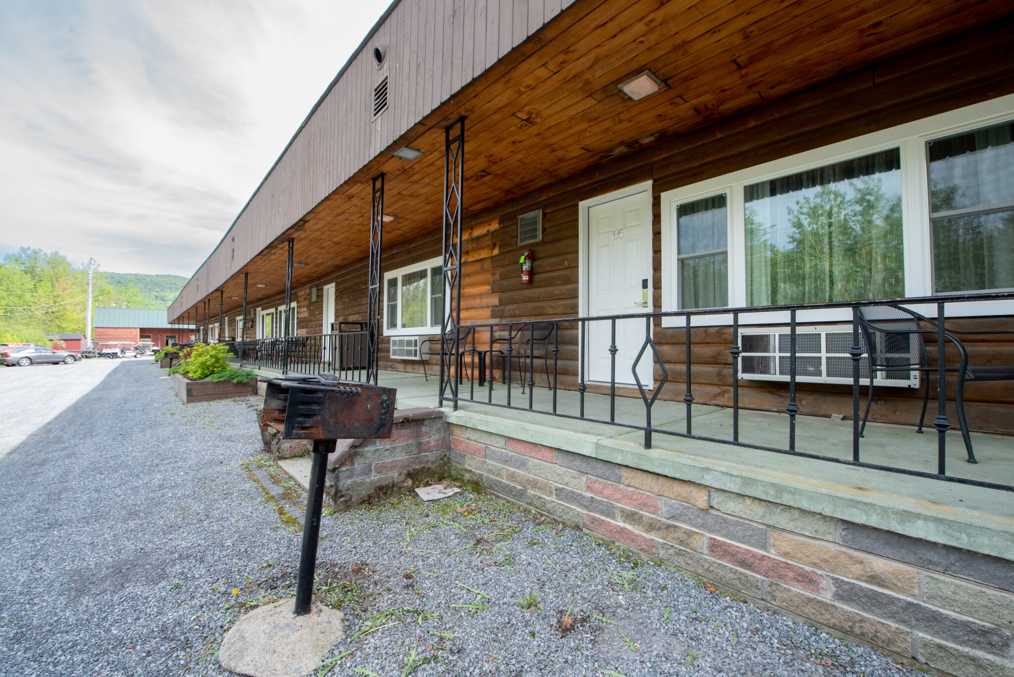A long, one-story building with a wooden exterior and a covered porch, surrounded by a parking lot and a grill.